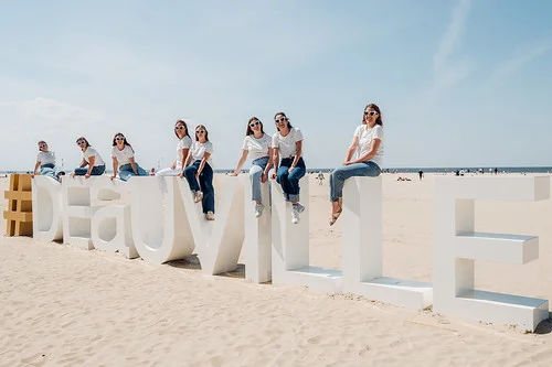 Groupe de femmes lors d’une chasse au trésor EVJF à Deauville et Trouville, posant sur les lettres géantes sur la plage.