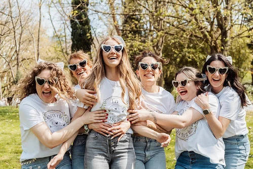 groupe de femmes en lunettes coeur riant et entourant la future mariee lors d’un evjf festif dans un parc a toulouse
