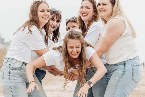 groupe de femmes en jean et t shirt blanc portant une amie en riant sur la plage