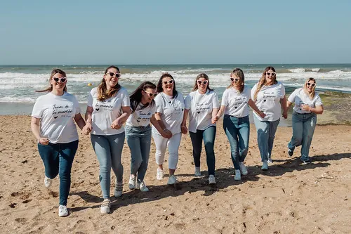 groupe de femmes en t shirt blanc et jean courant ensemble sur la plage de cabourg pendant un evjf