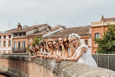 future mariee et ses amies en blanc posees sur un pont en briques a toulouse lors d’un evjf festif et complice