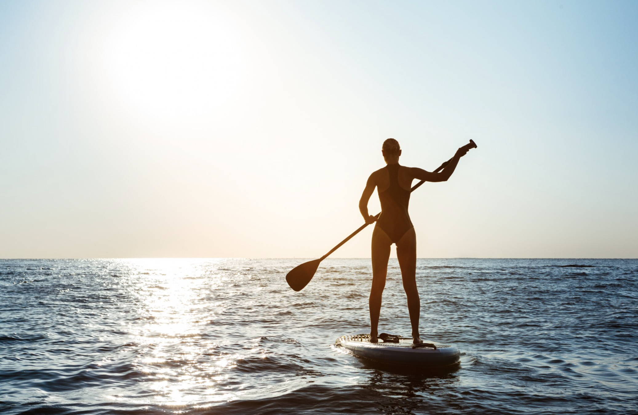 femme en tenue de bain, debout sur un paddle sur le bassin d’Arcachon lors d’un enterrement de vie de jeune fille.