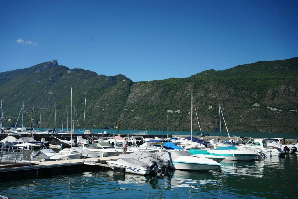 Bateaux de plaisance amarrés au port d’Aix-les-Bains, entourés de montagnes et d’un ciel bleu clair.