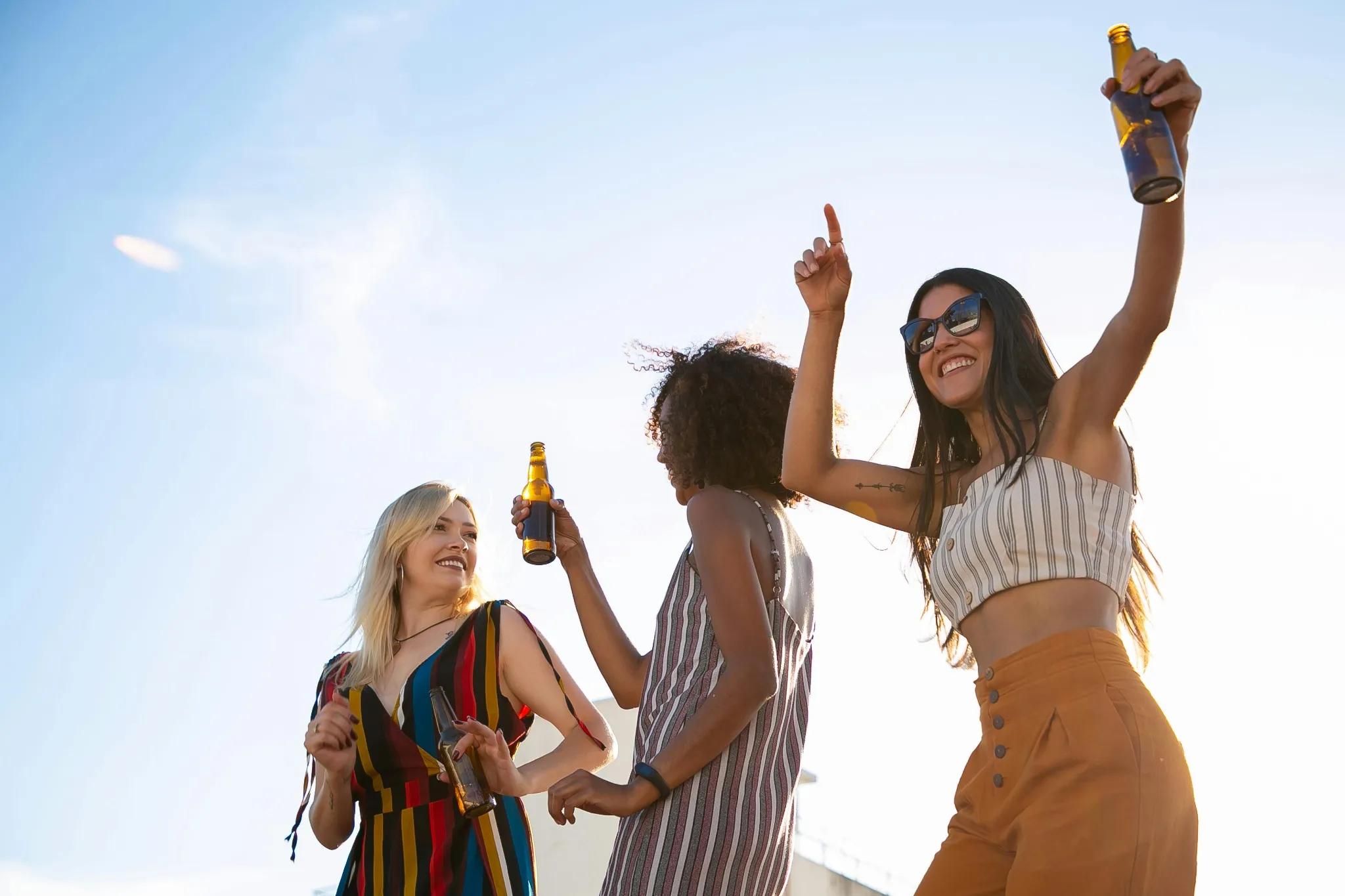 Trois participantes d’EVJF dansent et lèvent les bras sur un rooftop à Aix-en-Provence, ambiance ensoleillée.