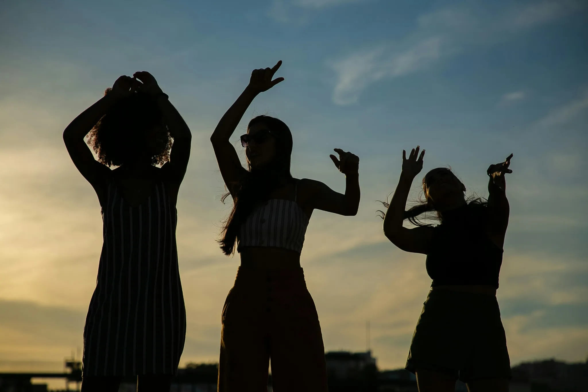 Silhouettes de trois amies qui dansent au soleil couchant à Aix-les-Bains.