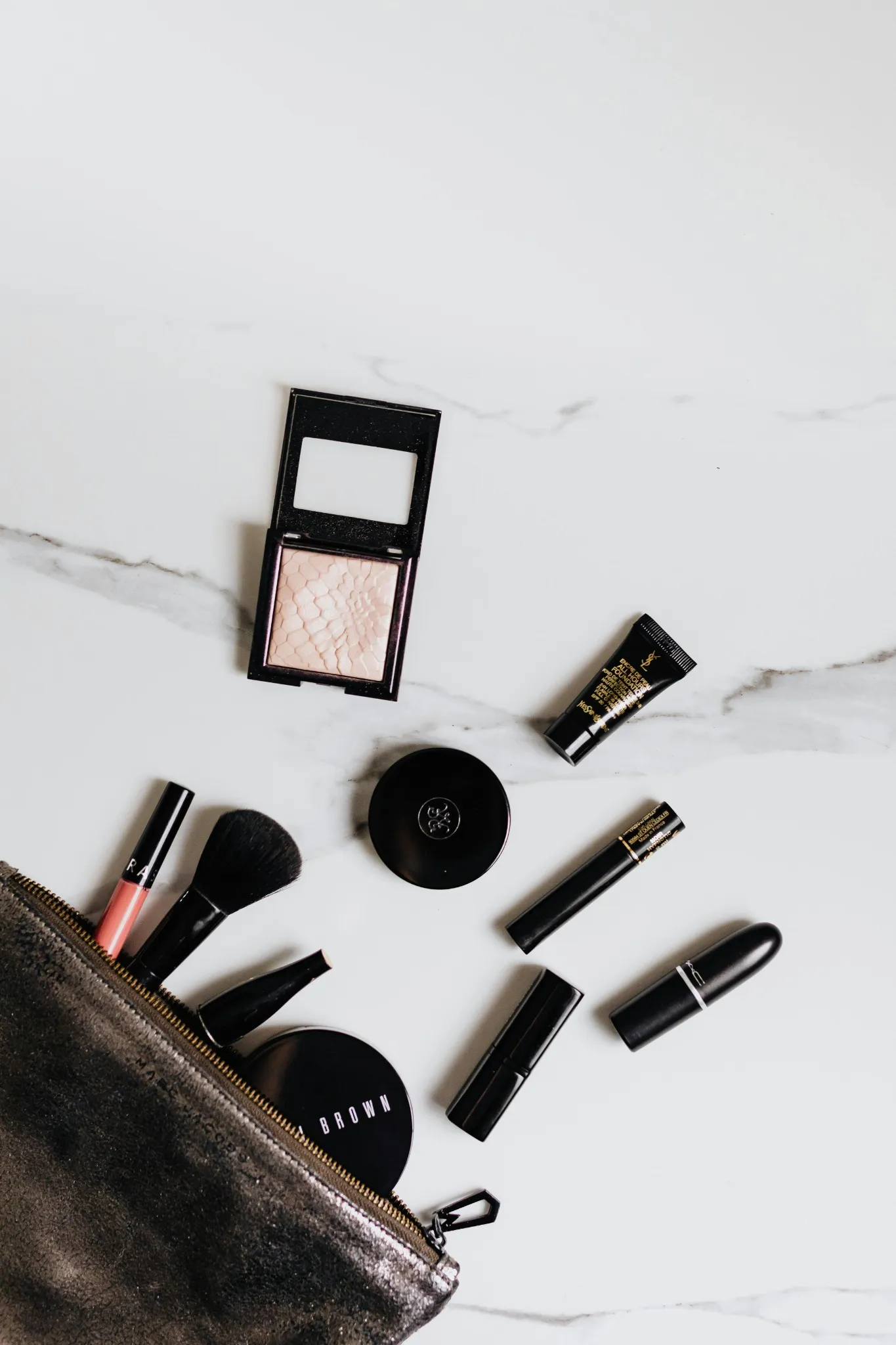 Trousse ouverte avec produits de maquillage sur fond marbré pour un EVJF à Angers