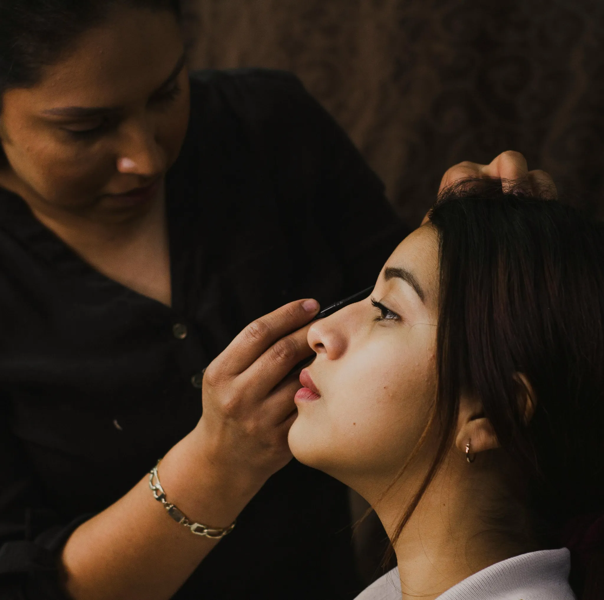 Gros plan d'une maquilleuse appliquant un eyeliner sur l'œil d'une cliente à Aix-les-Bains.