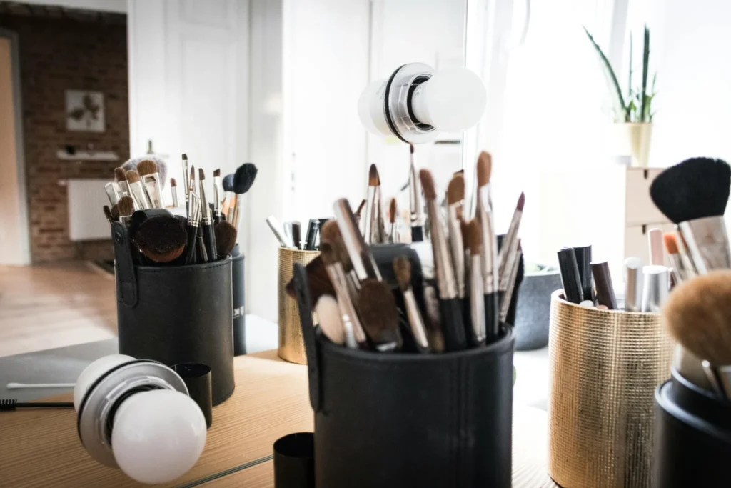 Pinceaux de maquillage rangés dans des pots devant un miroir, utilisés lors de prestations beauté à Aix-les-Bains.