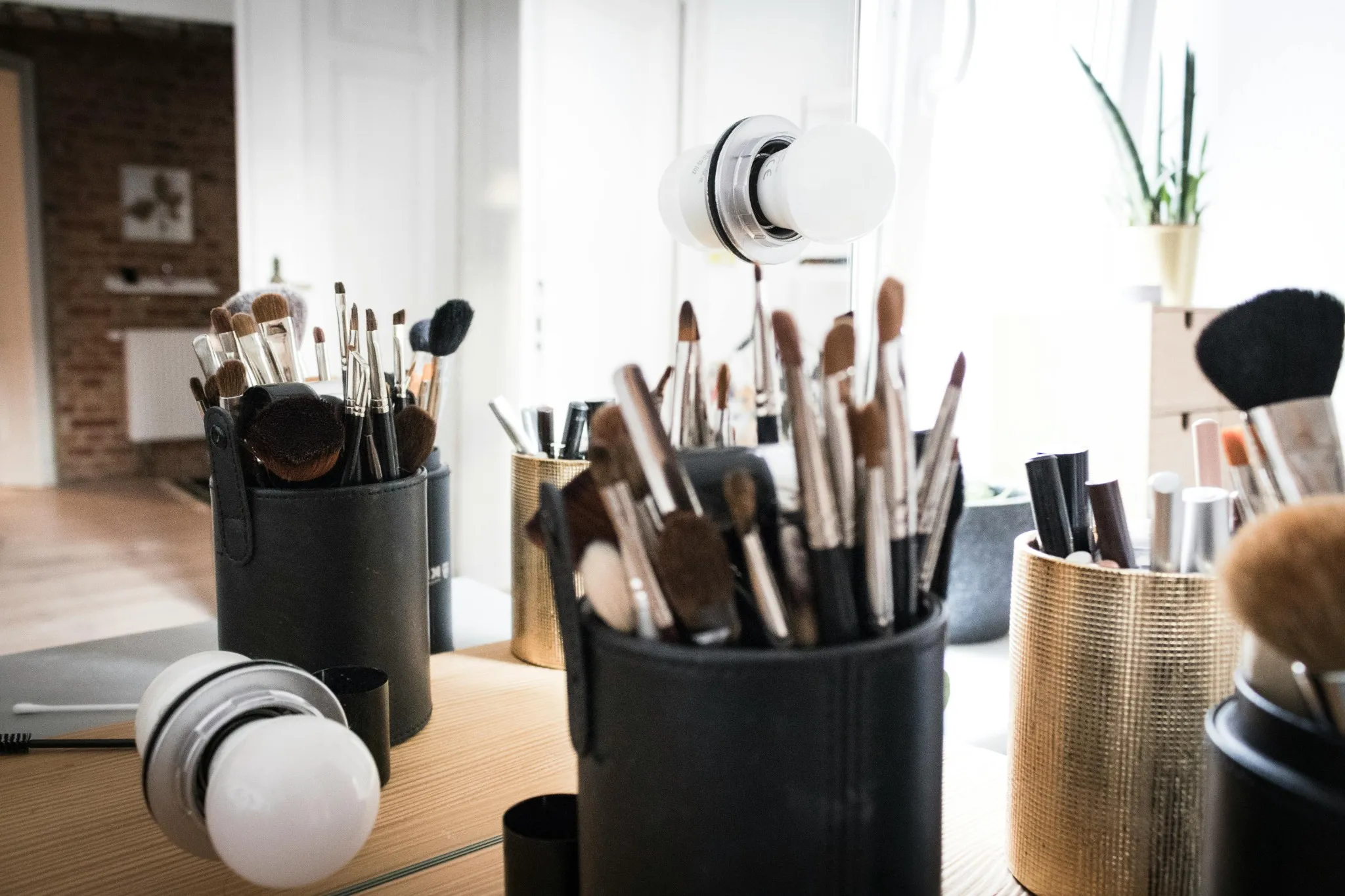 Pinceaux de maquillage rangés dans des pots devant un miroir, utilisés lors de prestations beauté à Aix-les-Bains.