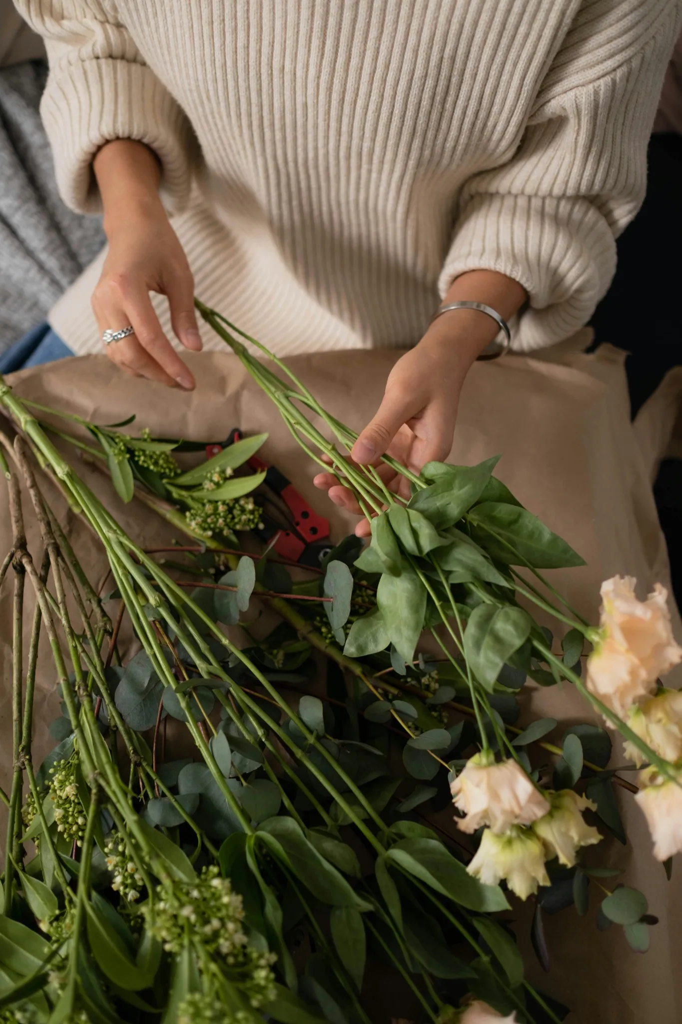 Mains coupant des tiges de fleurs blanches avec un sécateur lors d’un EVJF au Touquet
