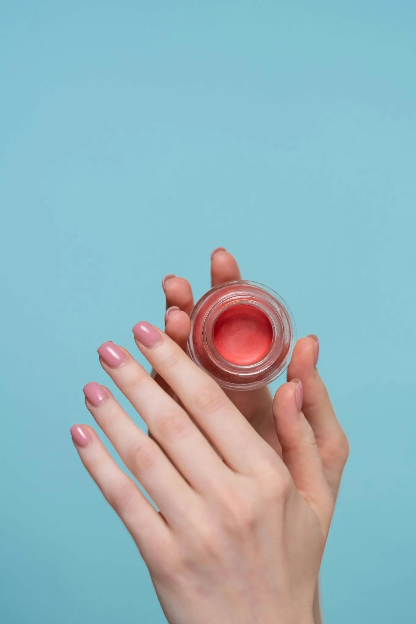 Mains féminines tenant un baume à lèvres rose lors d’un atelier à Reims
