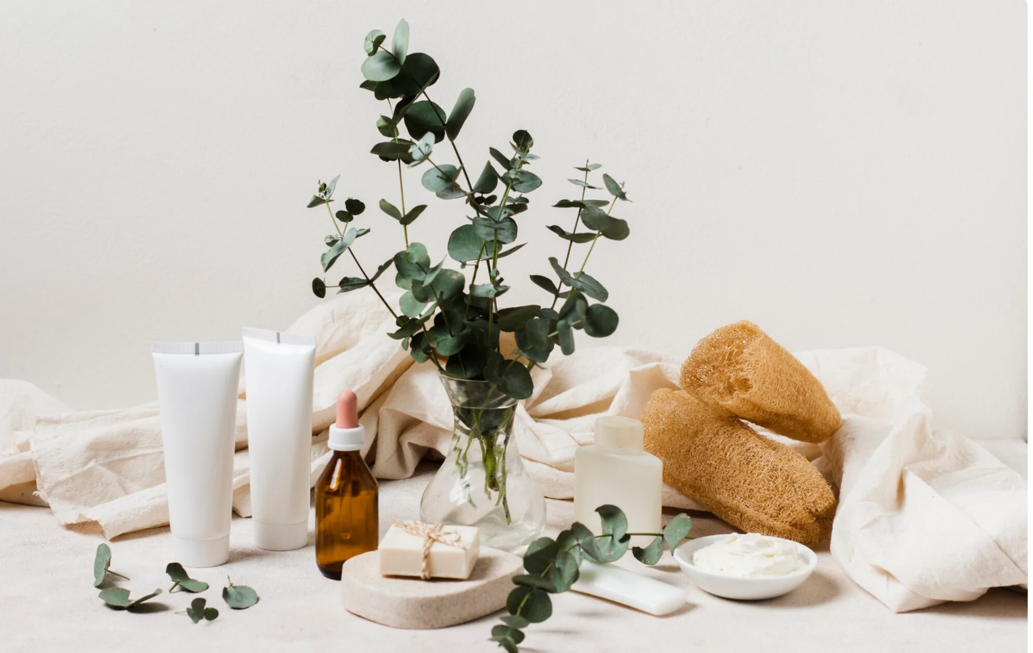 Produits de soin naturels avec eucalyptus et accessoires bien-être sur fond neutre, EVJF à Annecy.