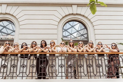Groupe de femmes alignées sur un balcon à Lyon formant des cœurs avec leurs mains lors d’un shooting photo EVJF.