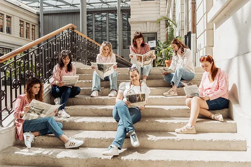 Groupe de femmes assises sur un escalier intérieur à Lyon, lisant des journaux .