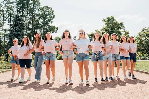 Groupe de femmes en t-shirts roses et shorts marchant ensemble au parc de la tête d'or à Lyon lors d’un shooting photo EVJF.