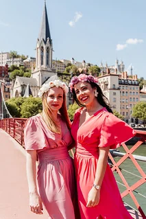 Deux femmes avec couronnes de fleurs posant sur une passerelle à Lyon lors d’un shooting photo EVJF en tenue rose.