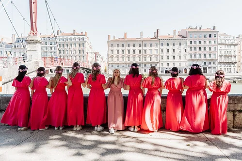 Groupe de femmes en robes roses de dos face à la Saône à Lyon lors d’un shooting photo EVJF.