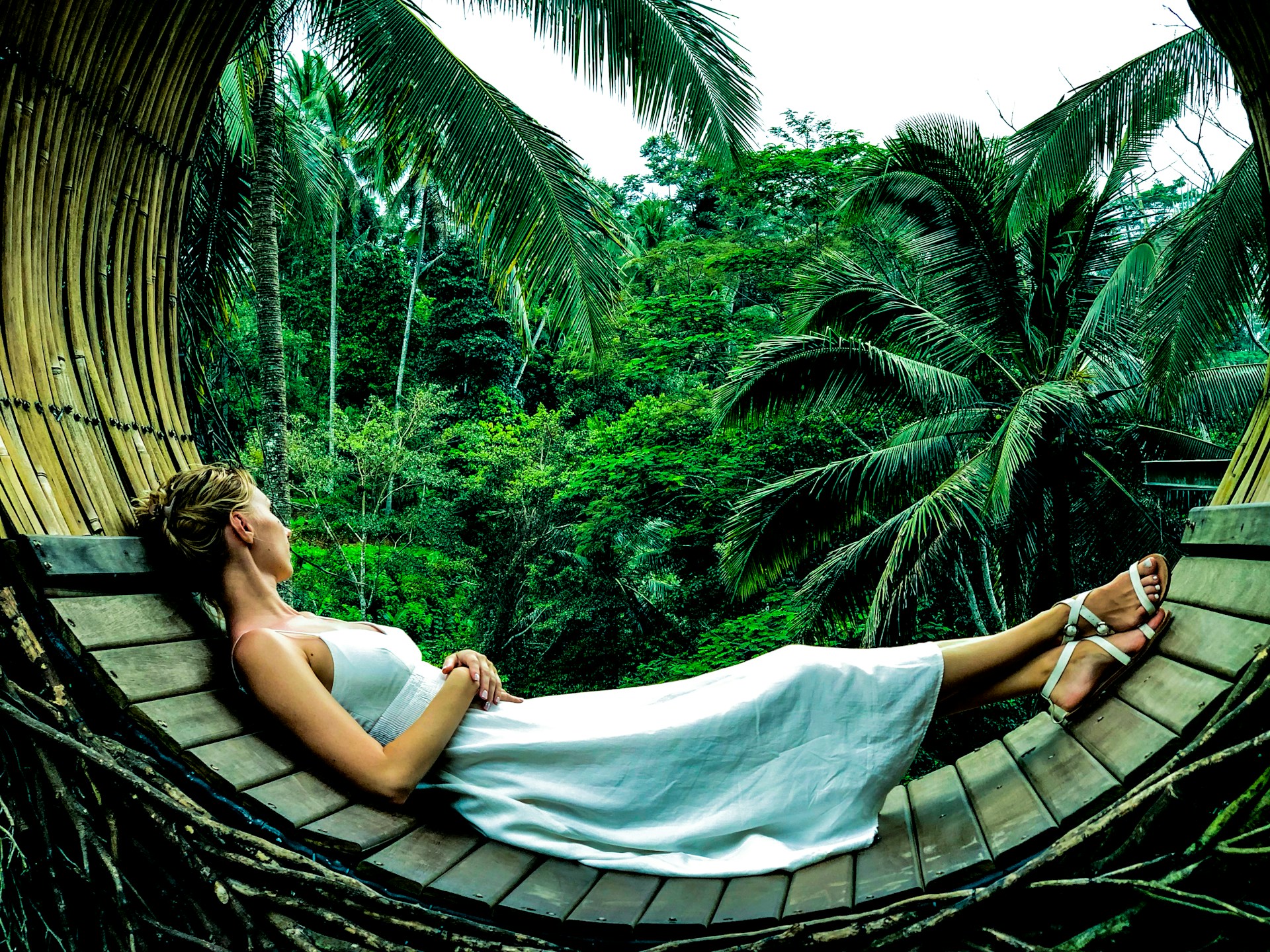Femme allongée dans un nid en bois face à une jungle tropicale