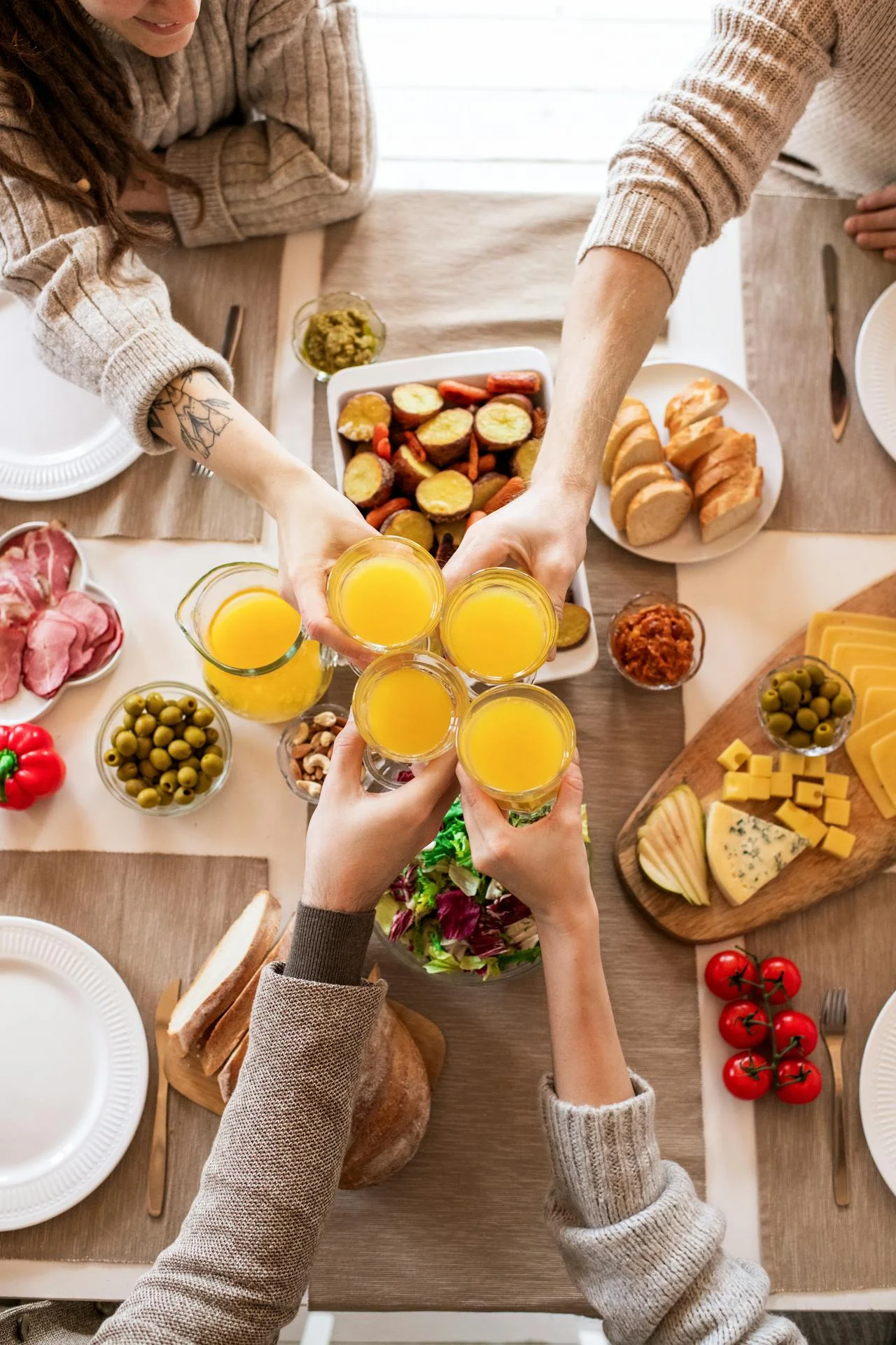 Amis trinquant avec des verres de jus d’orange autour d’un brunch festif EVJF à Paris