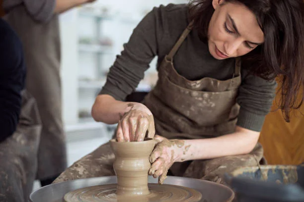 Activité artisanale poterie EVJF à Strasbourg, femme concentrée en train de façonner un vase en argile sur un tour de potier