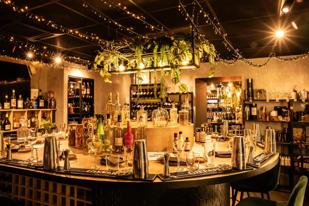 Bar convivial décoré de lumières et plantes avec verres et bouteilles pour un atelier cocktail