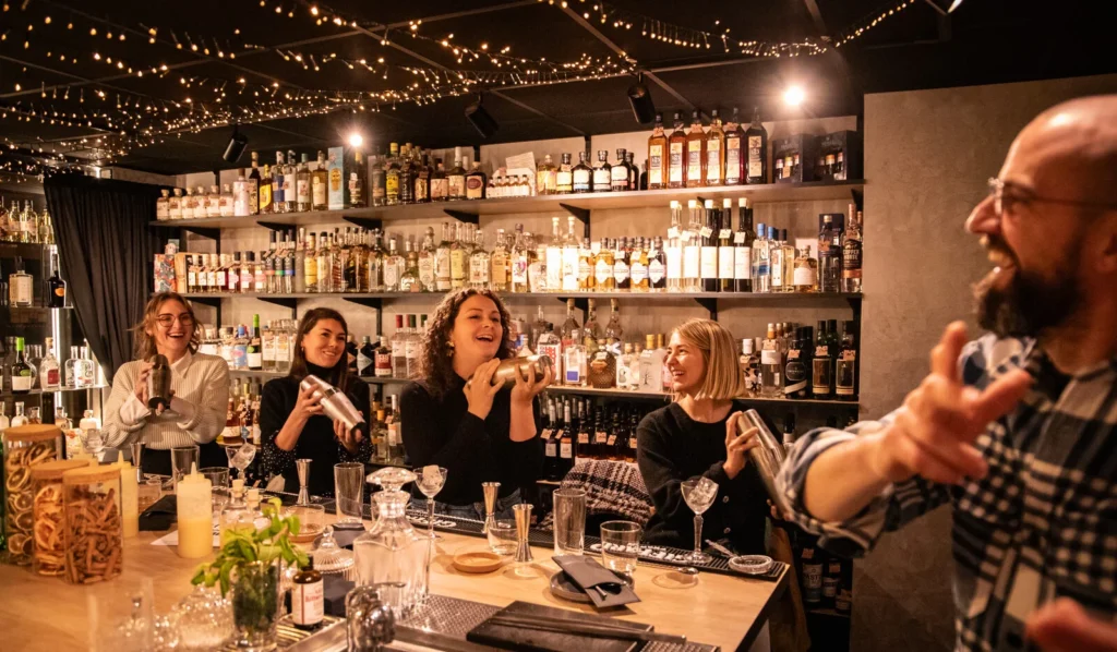 Groupe de participantes souriantes utilisant des shakers lors d’un atelier cocktail