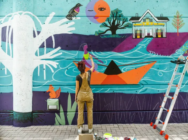 femme de dos peignant une fresque murale colorée lors d’un atelier street art evjf à toulouse