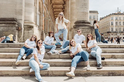 groupe de femmes assises sur les marches celebrant un brunch evjf a bordeaux en tenues blanches et jeans