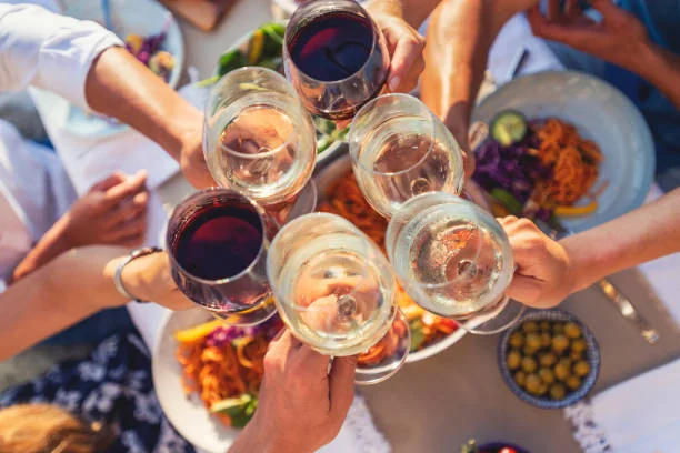 Amies levant leurs verres de vin rouge et blanc au-dessus d’une table garnie de plats méditerranéens lors d’un brunch EVJF à Nantes.