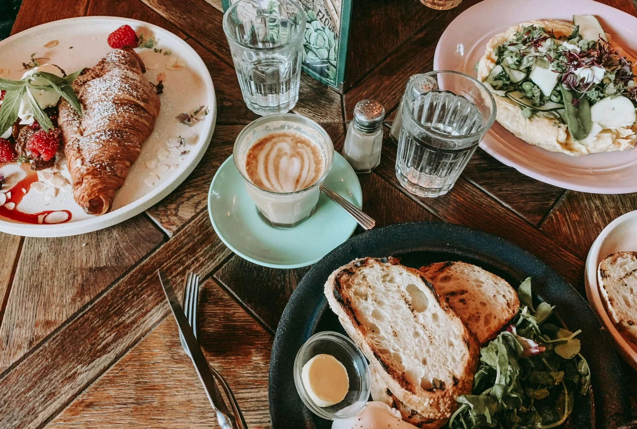 Croissant garni de fruits rouges et café latte sur une table de brunch
