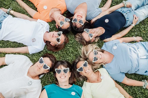 Groupe de femmes allongées dans l’herbe avec des lunettes cœur 