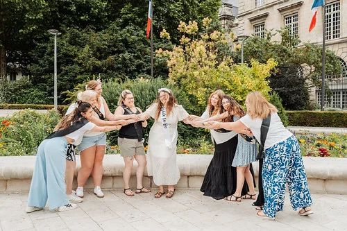 Amies en cercle tirant la future mariée en riant lors d’une chasse au trésor EVJF à Rouen