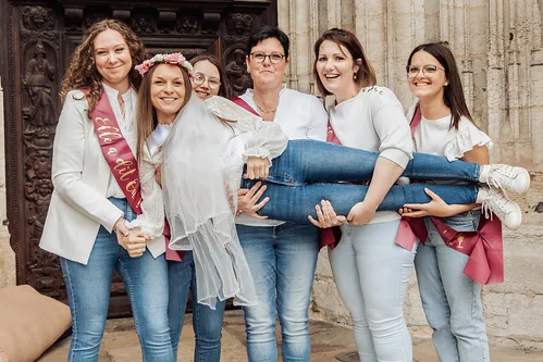 Future mariée en tenue blanche portée par ses amies souriantes 