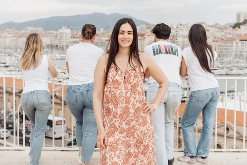 femme en robe pose devant ses amies tournant le dos avec vue sur le vieux port de marseille lors d un evjf