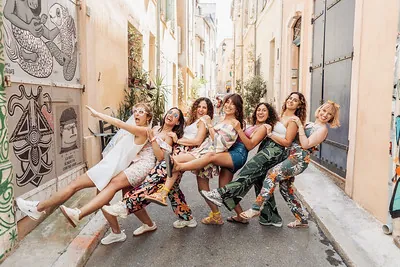 groupe de femmes souriantes en pleine pose festive dans une rue coloree de marseille pendant un evjf
