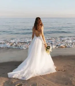 Chasse au trésor EVJF Nice Le trésor de la mariée ? Jeune femme en robe de mariée face à la mer tenant un bouquet