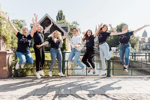groupe de femmes sautant en l air sur un pont dans une ambiance festive et complice