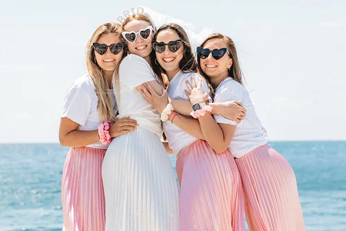 Clip vidéo EVJF à Nice avec quatre amies en jupe rose et t-shirt blanc, souriantes et enlacées en bord de mer