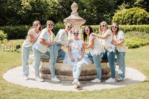 Groupe de femmes en jeans et t-shirts blancs autour d’une fontaine lors d’un clip video evjf à Reims en extérieur