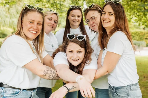 Groupe de femmes en t-shirts blancs posant ensemble en extérieur pendant un clip video evjf à Reims