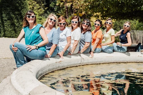 Groupe de femmes portant des lunettes en forme de cœur posant au bord d’une fontaine 