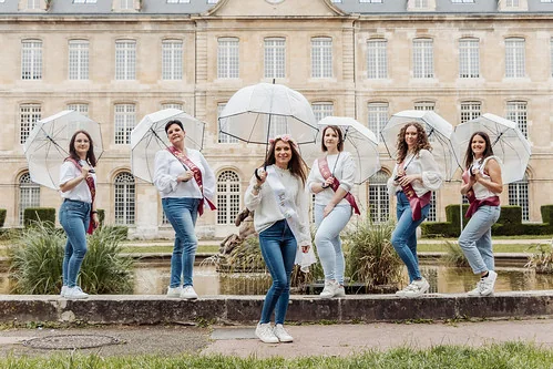 Femmes posant avec des parapluies blancs devant un bâtiment historique lors d’un clip vidéo EVJF à Rouen