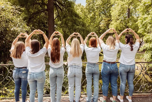 clip vidéo evjf à bordeaux avec groupe de femmes en jean et t-shirt blanc faisant des cœurs avec les mains dans un parc verdoyant