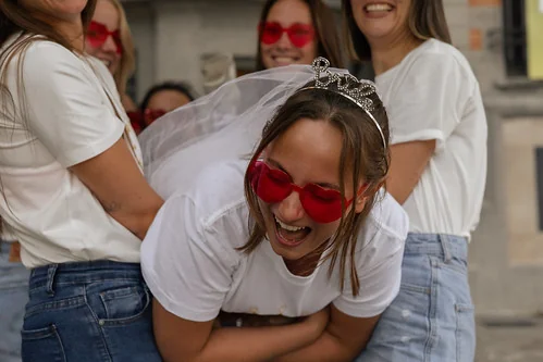 future mariee portant un voile et des lunettes rouges rit avec ses amies pendant un clip video evjf lille