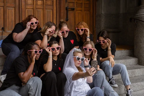 future mariee et amies en lunettes coeur prenant un selfie  sur des marches