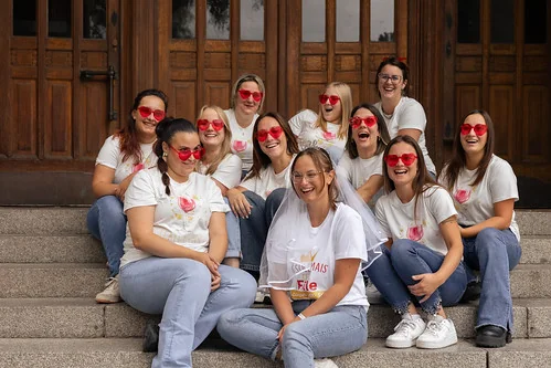 groupe de femmes portant des lunettes rouges assises sur des marches pendant un clip video evjf lille