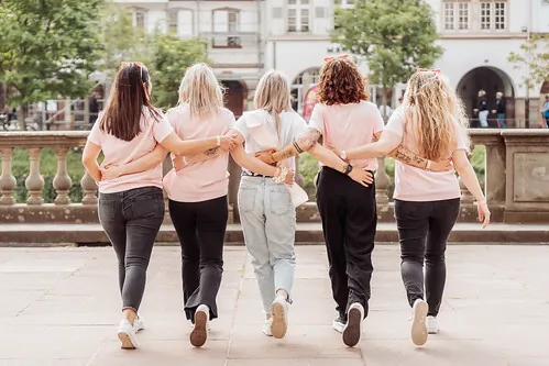 groupe de jeunes femmes en t shirts roses marchant bras dessus bras dessous lors d un clip video evjf a strasbourg