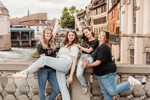 groupe de jeunes femmes posant joyeusement sur un pont de la petite france lors d un clip video evjf a strasbourg
