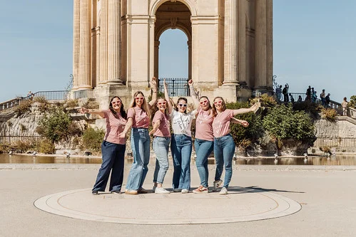 Groupe de jeunes femmes célébrant un EVJF à Montpellier devant un monument historique sous le soleil