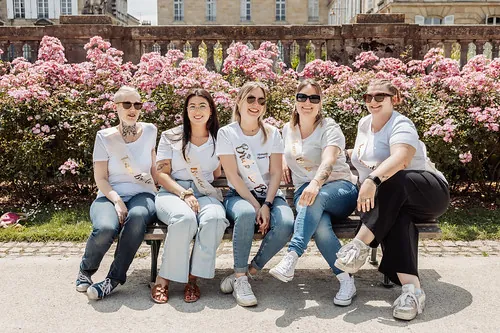 comment organiser un evjf à bordeaux : groupe d’amies souriantes assises sur un banc devant des rosiers dans un parc